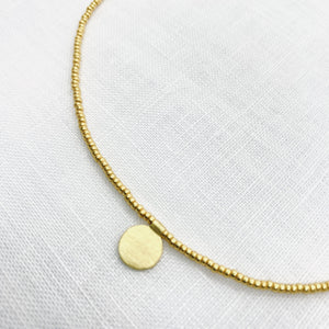 THE MAKERY SHORT BEADED GOLD NECKLACE WITH A BRASS DISK